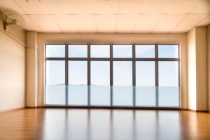 Perspective view of empty studio with wooden flooring illuminated with light from windows